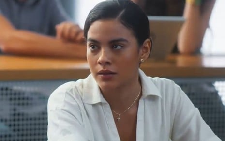 Bella Campos caracterizada como Jenifer; ela tem o semblante sério e apreensivo em cena de Vai na Fé