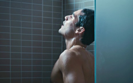 O ator Nicolas Prattes está pelado tomando um banho em cena  de Todas as Flores como seu personagem Diego