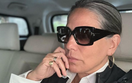Gloria Pires, de óculos escuros, está dentro de um carro
