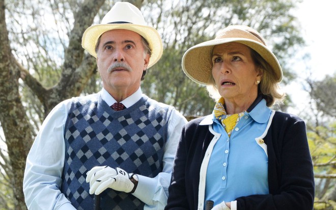 Otávio (Tony Ramos) está ao lado de Charlô (Irene Ravache); ambos usam roupas para jogar golfe