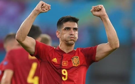 Gerard Moreno com camisa vermelha da Espanha com os dois braços levantados e punhos cerrados para o alto ao lado da cabeça em partida pela Eurocopa
