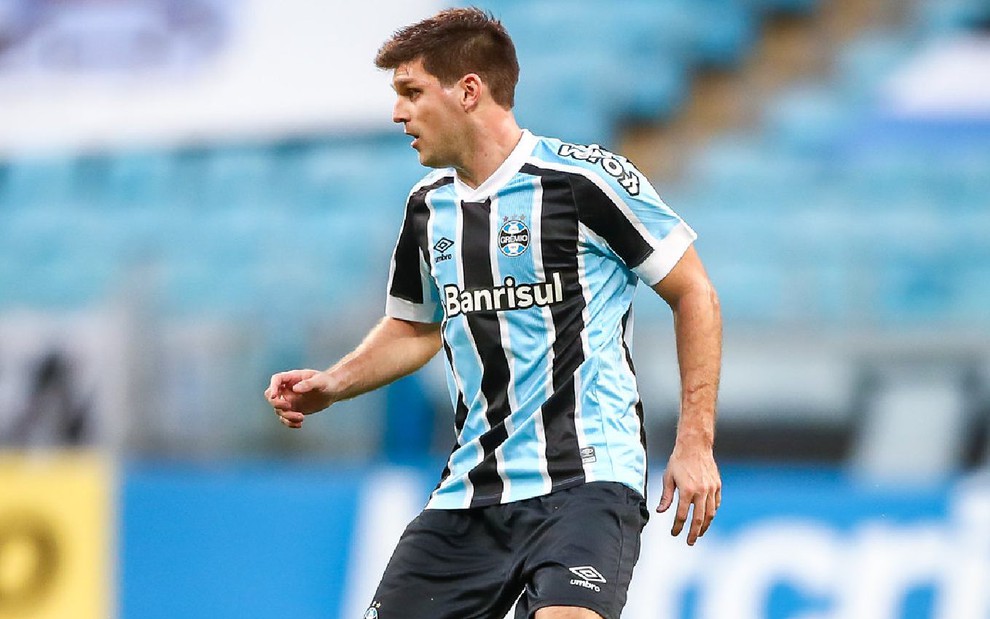 Kannemann com calção preto e camisa azul, branca e preta do Grêmio e olhando para a esquerda em partida