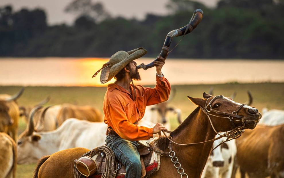 Irandhir Santos surge montado em cavalo e sopra berrante em cena de Pantanal