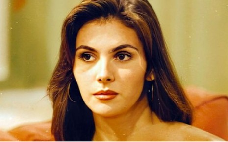 Lisandra Souto usa o cabelo repartido de lado e usa batom vermelho em foto de 1990