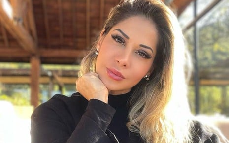 Maíra Cardi usa uma blusa preta e encara a câmera, séria, com os cabelos jogados loiros jogados para o lado esquerdo