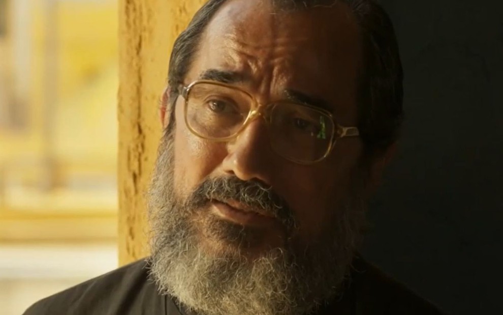 Nanego Lira com expressão séria em cena como padre Zezo na novela Mar do Sertão