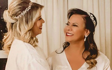 Vestida de branco, a cantora Marilia Mendonça abraça a mãe, Ruth Moreira