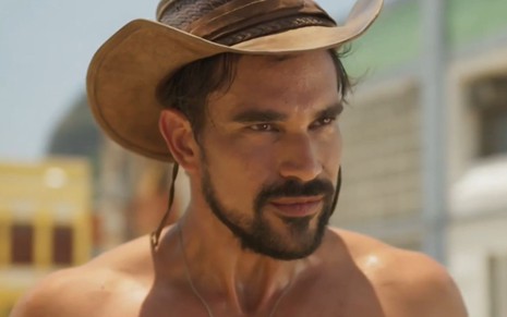 Matteus Cardoso sorri e está com chapéu de boiadeiro em cena como Joel na novela Mar do Sertão