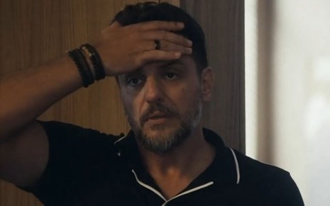 Em cena de Travessia, Rodrigo Lombardi está com a expressão de descontentamento, com a mão na testa
