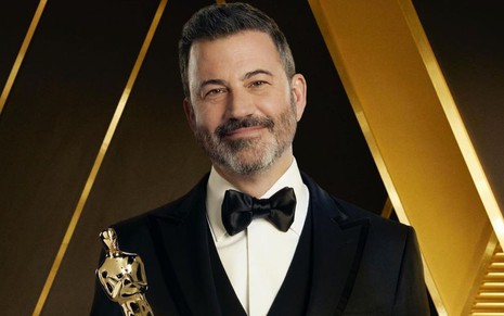 Imagem do comediante Jimmy Kimmel vestindo terno preto e segurando estatueta do Oscar