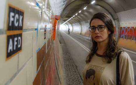 Priscila Sztejnman está séria em uma estação de trem alemã em cena do filme Segundo Tempo