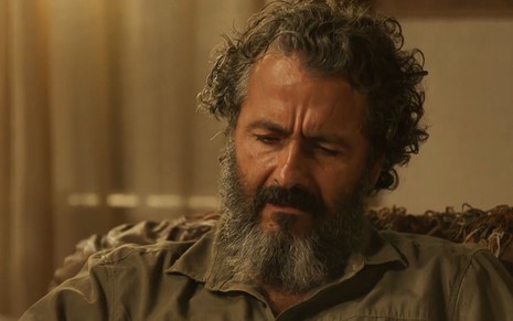 O ator Marcos Palmeira como José Leôncio em Pantanal; ele está sentado, olhando para baixo com cara de moribundo