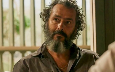 O ator Marcos Palmeira como José Leôncio em Pantanal; ele está sentado, olhando para frente com cara de atenção