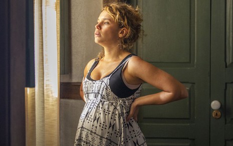 Bruna Linzmeyer, com as mãos apoiadas na cintura, grava cena de Madeleine grávida na novela Pantanal