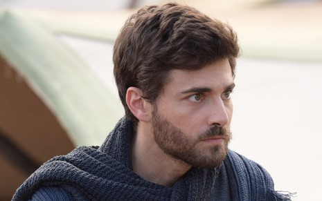 Miguel Coelho em cena de Gênesis: ator está caracterizado como Jacó e olha com seriedade para alguém fora do quadro