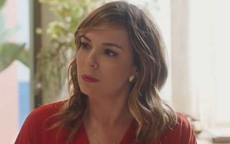 Clara (Regiane Alves) com expressão séria e blusa vermelha em cena de Vai na Fé