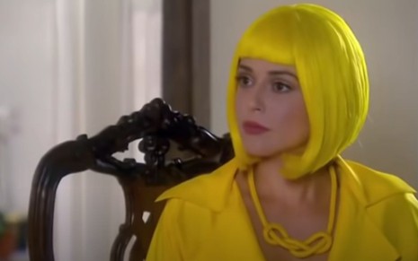 Priscila Sol grava cena de peruca amarela, com expressão séria, como Estefânia de Carinha de Anjo