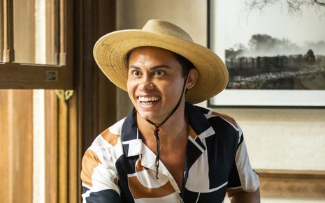 O ator Silvero Pereira como Zaquieu em Pantanal; ele está de chapéu olhando para frente e sorrindo