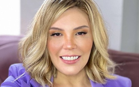 Foto do rosto de Simony; a cantora sorri e usa peruca loira