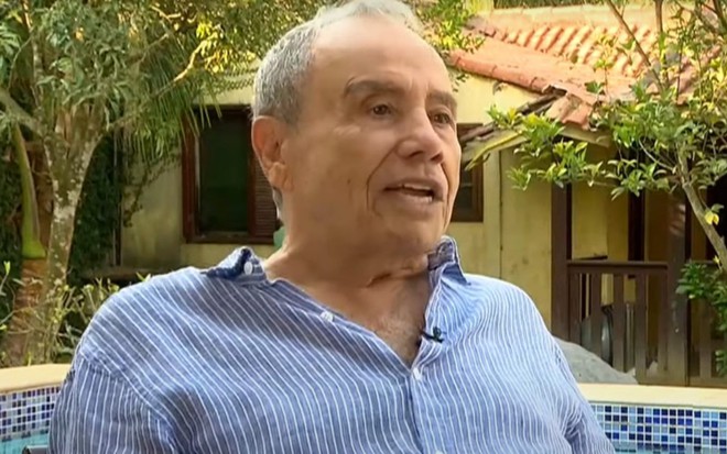 Stênio Garcia de camisa azul, em parte externa de uma casa, durante entrevista para a Record