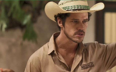 O ator José Loreto como Tadeu em Pantanal; ele está de chapéu e olha para o lado com cara de raiva e fúria