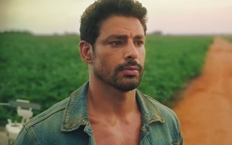O ator Cauã Reymond usa camisa surrada e está aparentemente suado em cena da novela Terra e Paixão como Caio