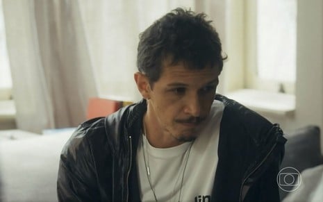 Em cena de Travessia, Rafael Losso usa casaco preto, blusa branca e está com a expressão de preocupação
