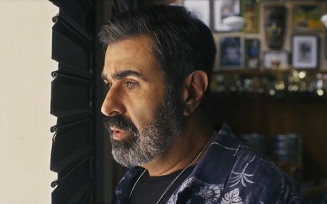 O ator Orã Figueiredo de perfil, com expressão séria, em cena de Travessia