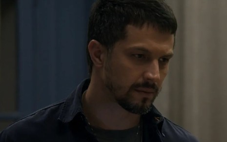 O ator Romulo Estrela como Oto em Travessia; ele está de lado, olhando para frente com cara de pensativo