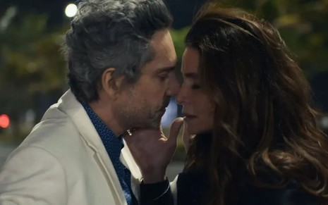 Os atores Alexandre Nero e Giovanna Antonelli como Stenio e Helô em Travessia; eles estão com os rostos encostados prestes a dar um beijo em cena