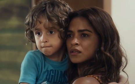 Tonho (Vicente Alvite) está no colo de Brisa (Lucy Alves) em cena da novela Travessia