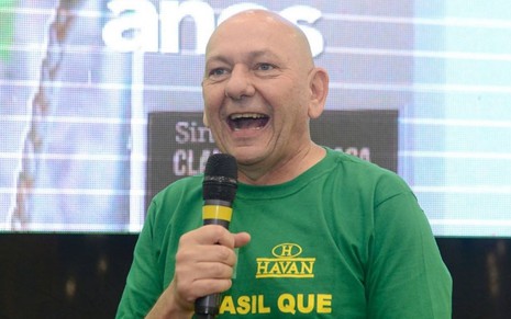 Luciano Hang, o 'véio da Havan', usa camisa verde com dizeres patriotas em amarelo; ele está com microfone em mãos