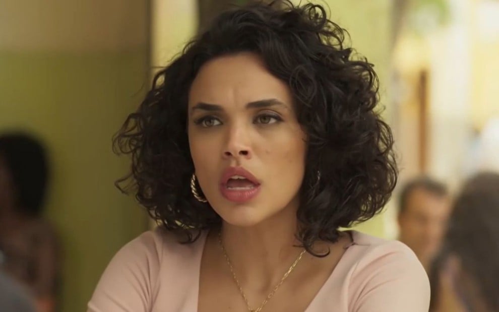 Giovana Cordeiro caracterizada como Xaviera; atriz usa um vestido vermelho e tem a expressão séria em cena de Mar do Sertão