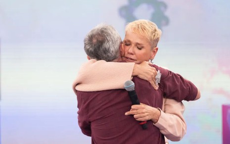 De costas, Serginho Groisman dá abraço em Xuxa Meneghel, que está emocionada