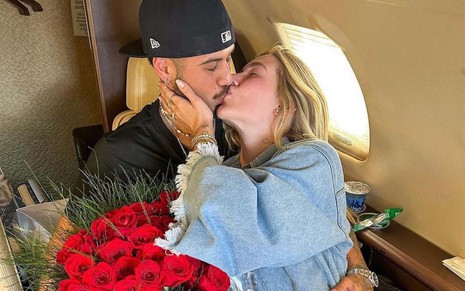 Zé Felipe e Virginia Fonseca se beijando num jatinho, com buquê de rosas na mão dele