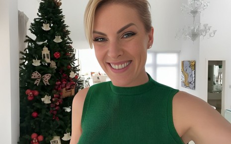 Ana Hickmann sorri com uma árvore de Natal ao fundo
