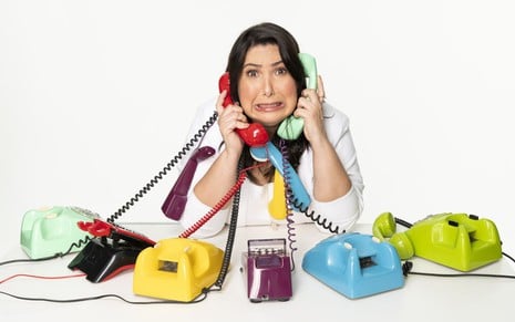 Mariana Xavier faz careta enquanto segura vários telefones em foto promocional da peça Antes do Ano que Vem
