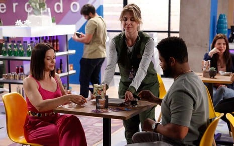 Vera (Bianca Rinaldi) e Bernardo (Fábio Ventura) estão sentados em mesa, enquanto Laura (Christiana Ubach) serve café