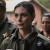 A brasileira Morena Baccarin tem expressão séria em cena de Fire Country; ela está vestida como xerife