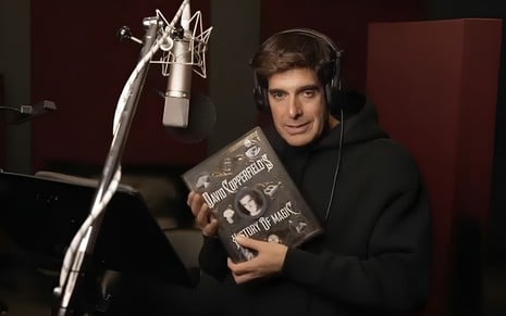 David Copperfield segura um livro de mágica em um estúdio de gravação de voz