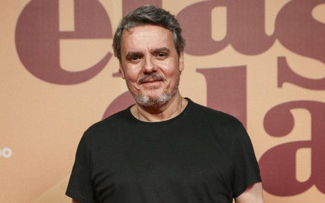 O ator Cassio Gabus Mendes usa camiseta preta e sorri ao posar no lançamento da novela Elas por Elas, da Globo