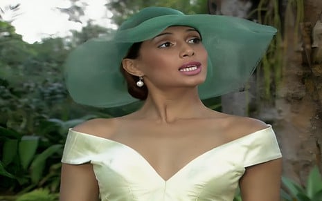 Camila Pitanga usa vestido verde claro e chapéu verde escuro em cena de Paraíso Tropical
