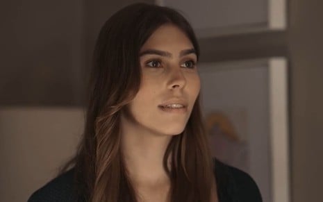 Gabriela Medeiros caracterizada como Buba; ela dá um leve sorriso e aparenta nervosismo em cena de Renascer