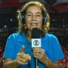 A jornalista Lilia Teles com um microfone com o logo da Globo na quadra da Viradouro