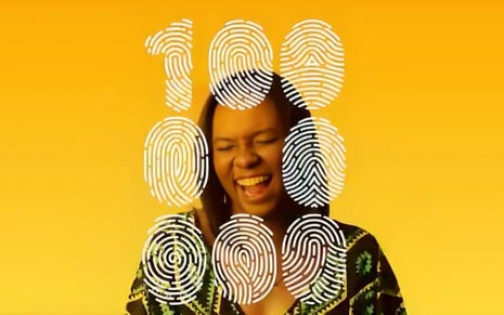 Imagem de vídeo da campanha 100 Milhões de Uns, lançada pela Globo em 2017: uma jovem negra sorri sob a impressão do número 100.000
