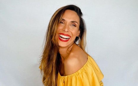 Manuela Duarte posa com uma blusa amarela; ela usa brunco prata e batom vermelho