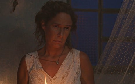 A atriz Andrea Beltrão em cena noturna, de camisola branca e expressão séria, em No Rancho Fundo
