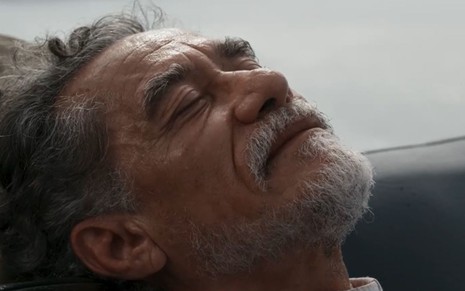 O ator Chico Diaz está com cabeça apoiada e olhos fechados em cena da morte do padre Santo na novela Renascer