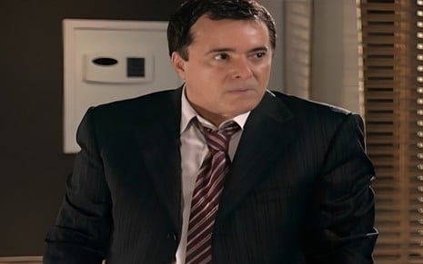 O ator Tony Ramos de terno, com expressão séria em cena de Paraíso Tropical