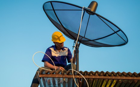 Antenista manipula antena parabólica do tipo telada, utilizada para captação do sinal da TV aberta na banda C